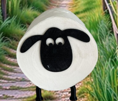 Schaf mit schwarzem Gesicht und großen Augen vor einem grünen Weg.